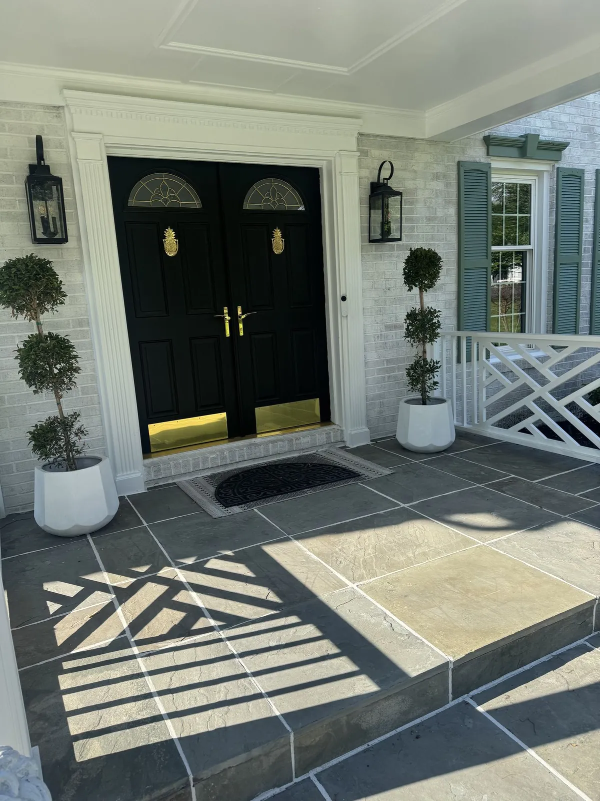 Front porch with black double doors and topiaries